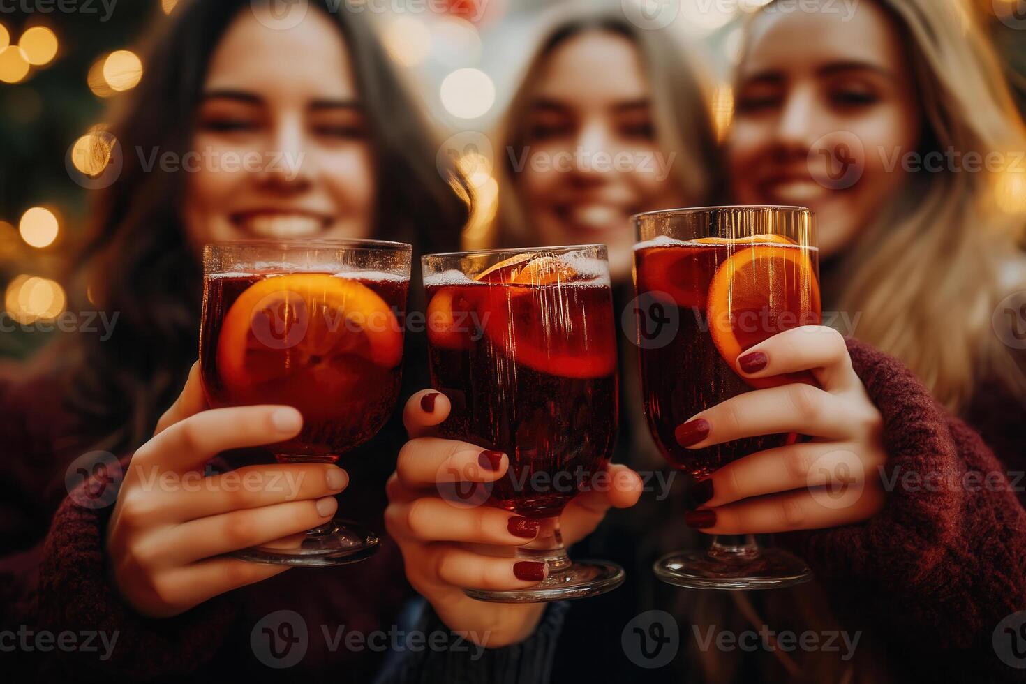 Group of young friends drinking mulled wine with orange at christmas market, festive background, bokeh, lights photo