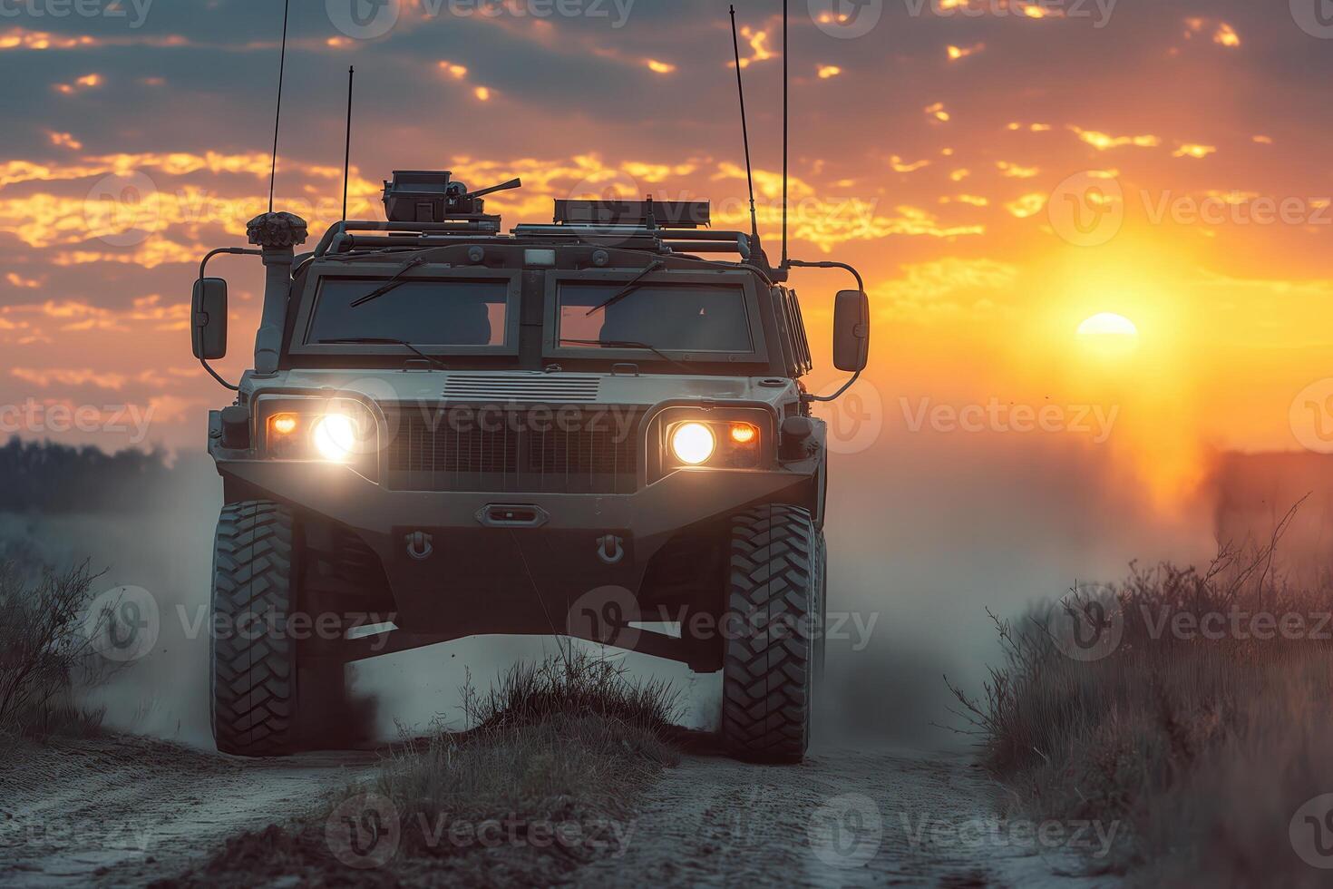 Military vehicle driving on a dirt road during sunse photo