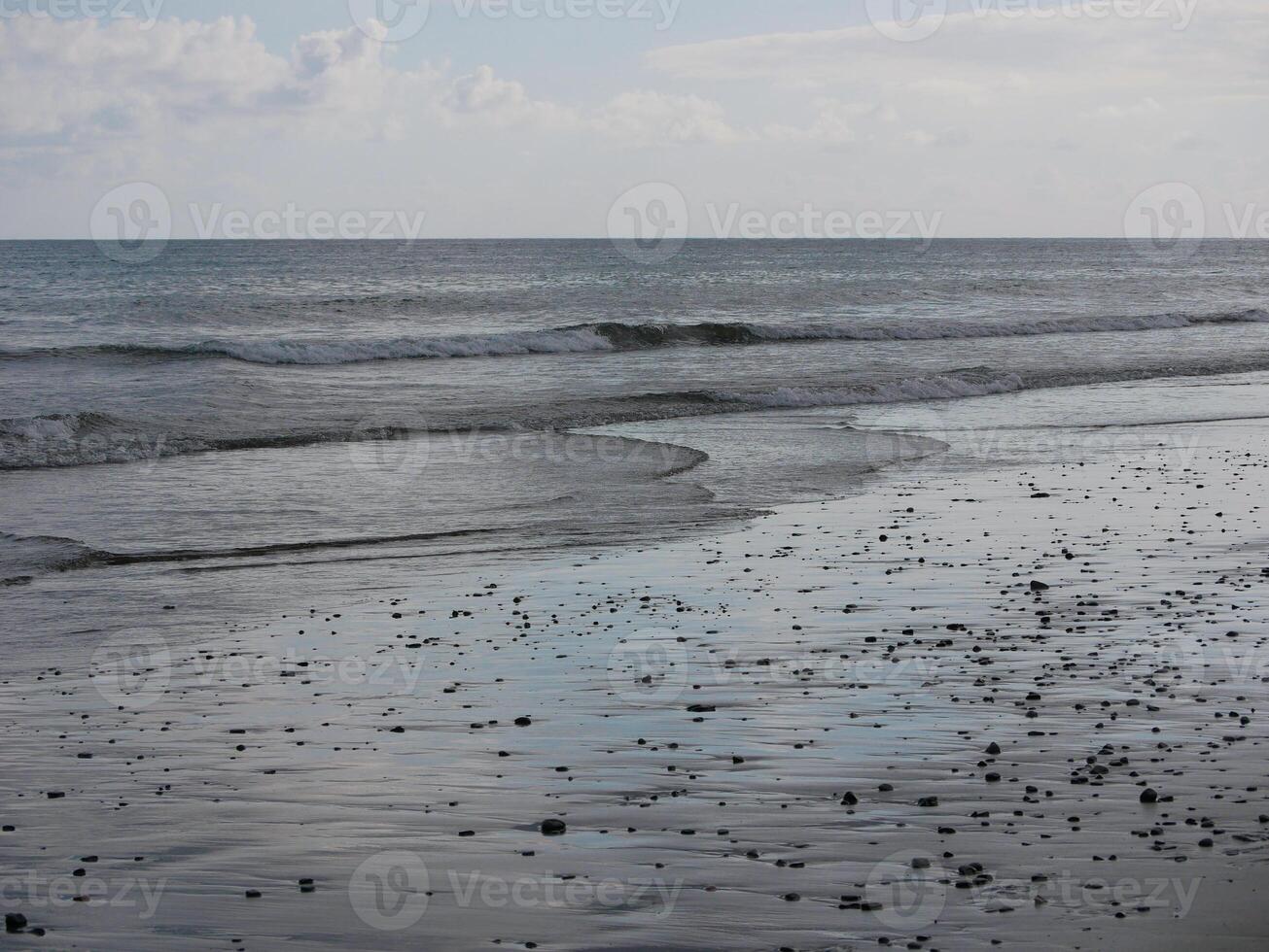 Seashore in sunlight with reflections on wet sand photo