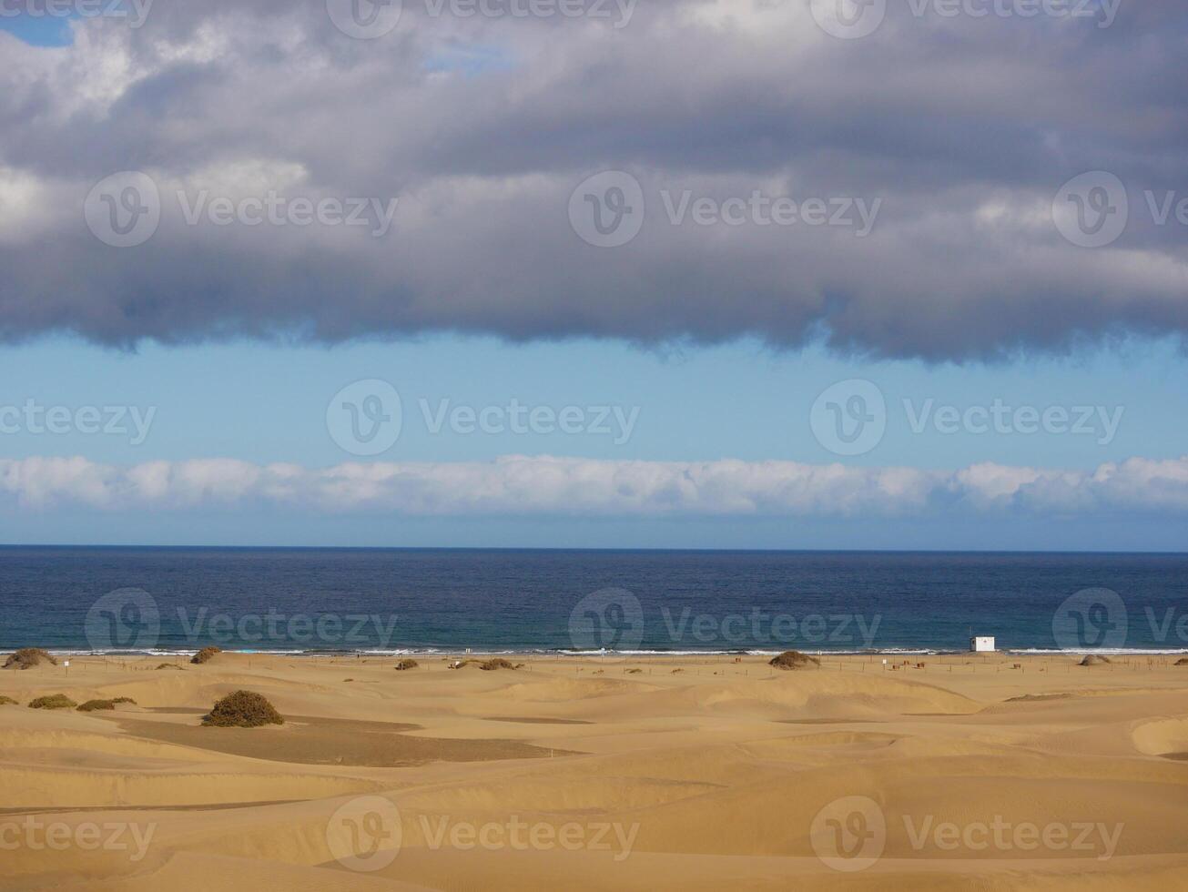 Sandy beach in Maspalomas, Gran Canaria at dusk with cloudy sky. Seascape background wallpaper with copy space photo