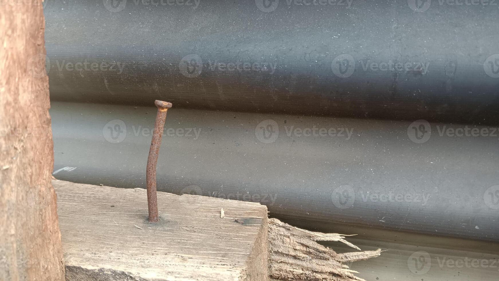 A close-up shot of a rusty nail hammered into a piece of weathered wood. photo