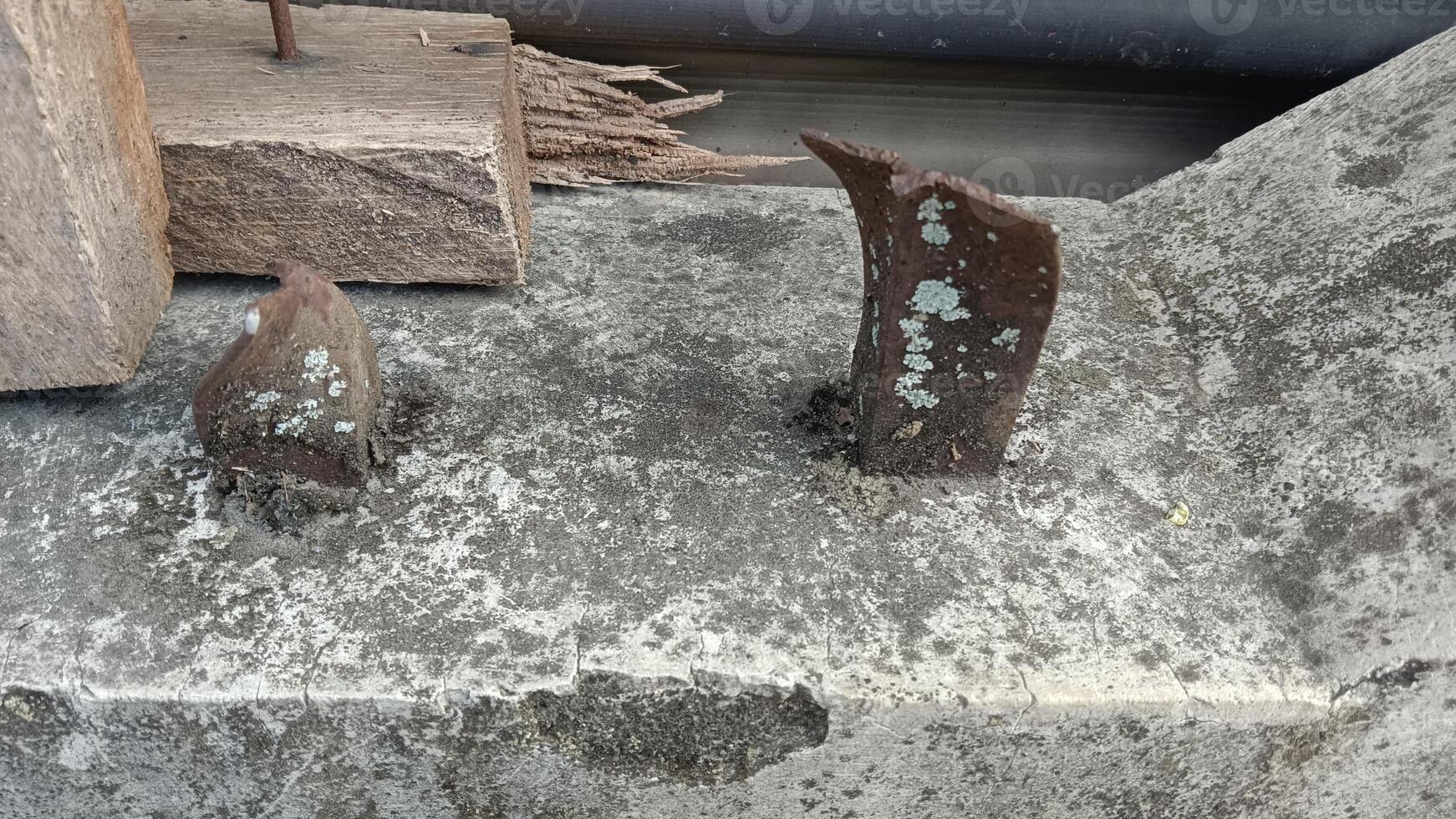 Two rusty metal pieces sticking out of a concrete surface. photo