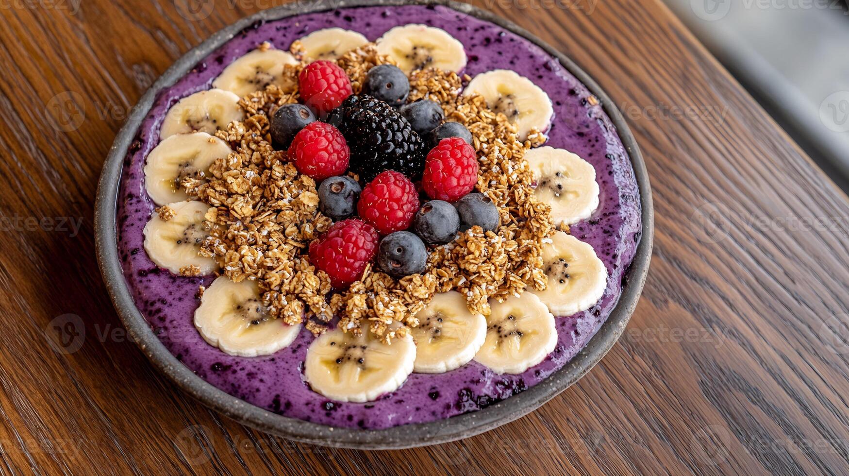 A bowl of blueberry smoothie with bananas, raspberries and granola photo