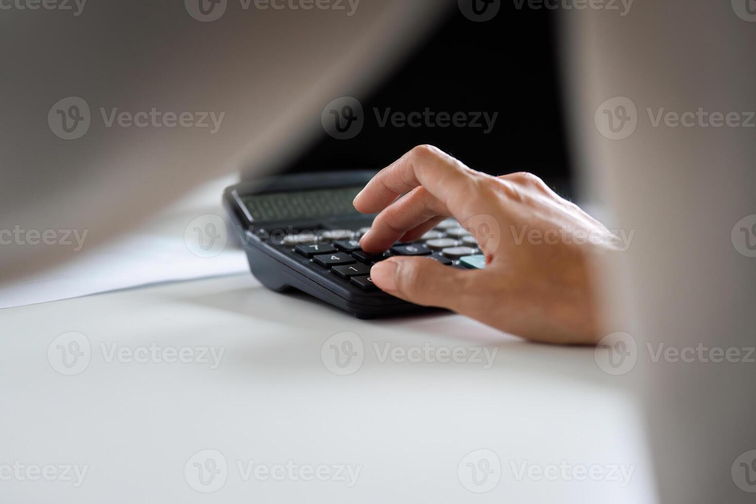 Focused Businesswoman Using Calculator for Financial Analysis in Modern Office Setting photo