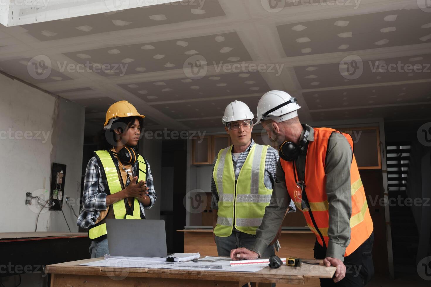 Engineering Team Planning Construction Work Indoors with Blueprints and Safety Gear in Modern Building Site photo