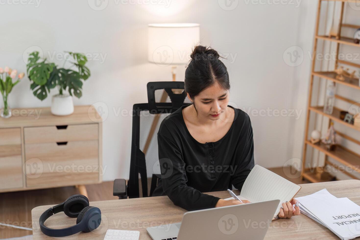 Woman Planning Finances from Home with Laptop and Notebook in Modern Home Office Setting photo