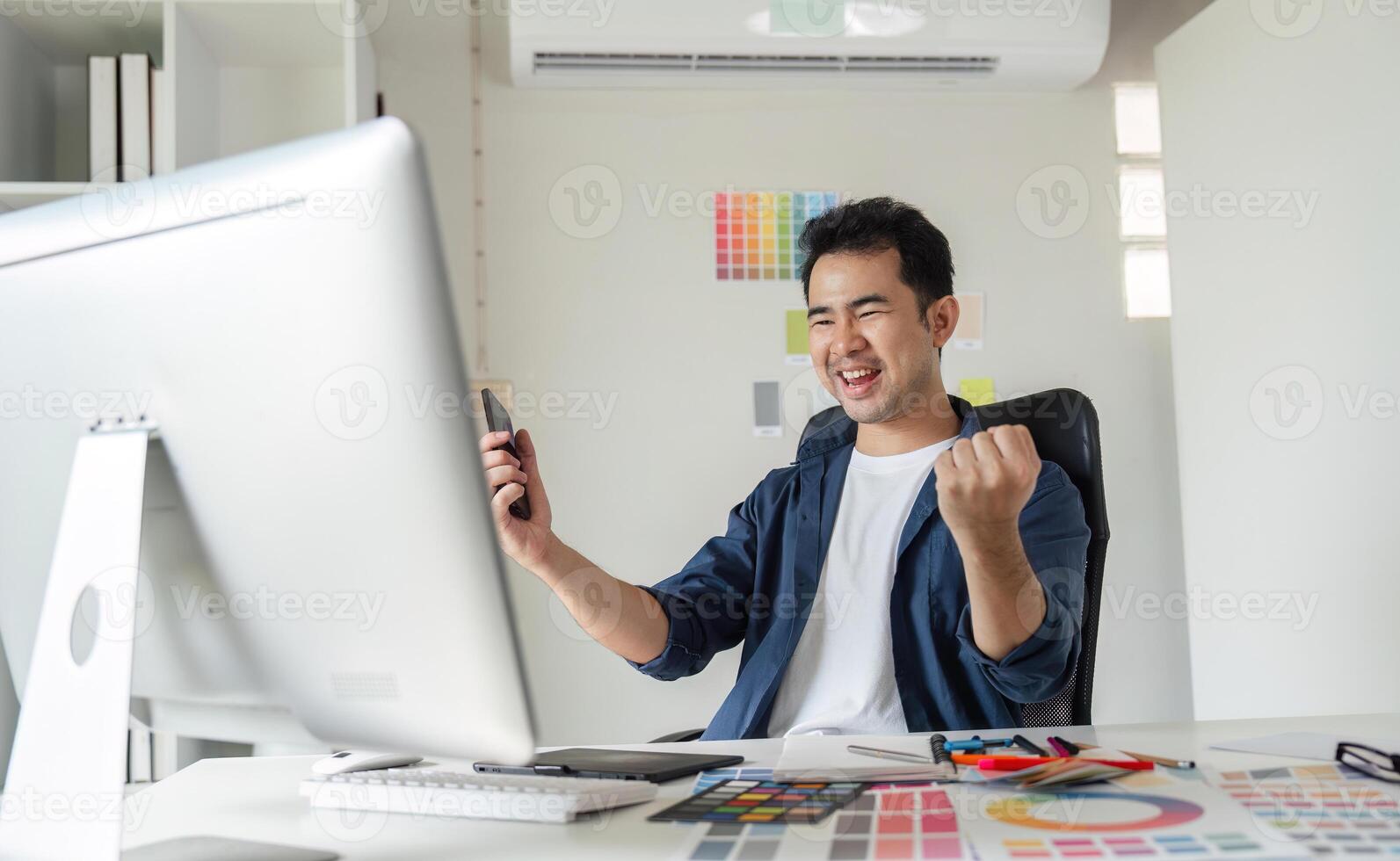 Young Male Graphic Designer Enthusiastically Working on Creative Project at Modern Workspace with Computer and Design Tools photo