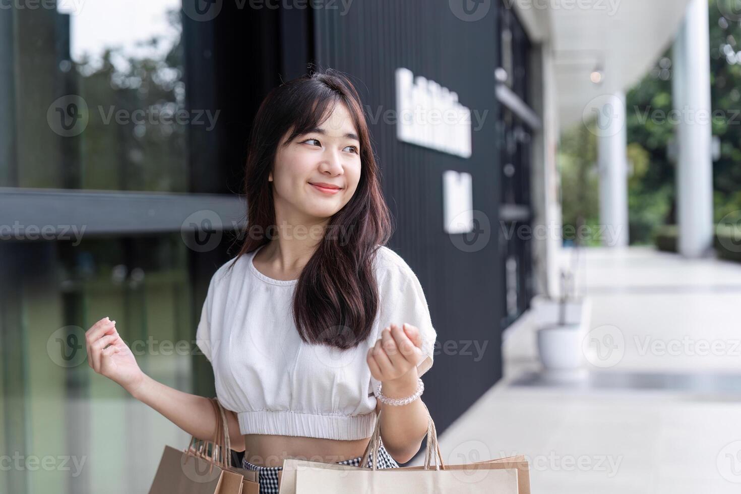 Charming Young Woman Enjoying a Shopping Spree with Paper Bags in a Modern Shopping Mall Setting photo