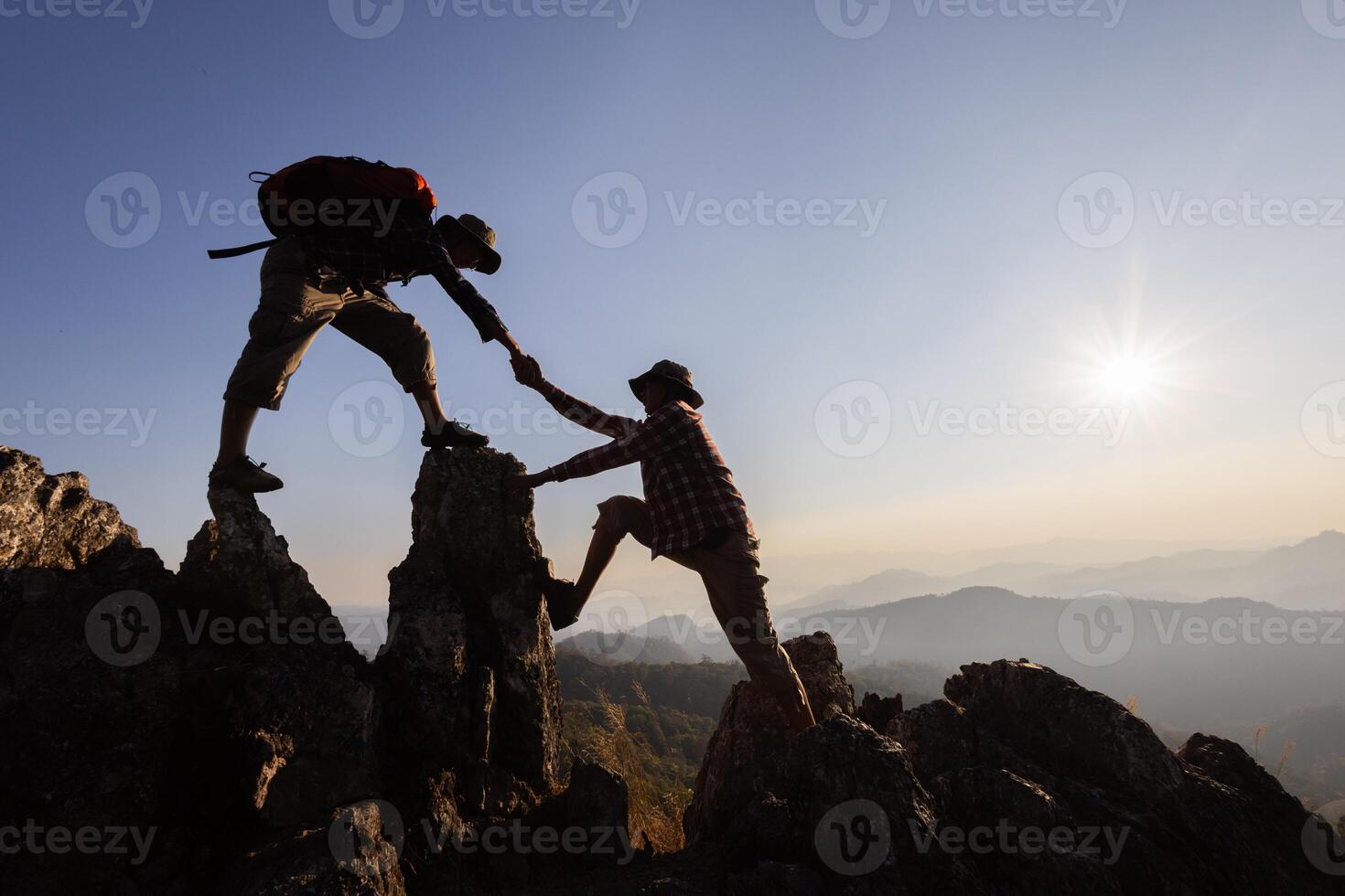 Silhouette of People helping on peak mountain and sunrise background climbing team work success business concept. People on peak mountain climbing helping team work. photo