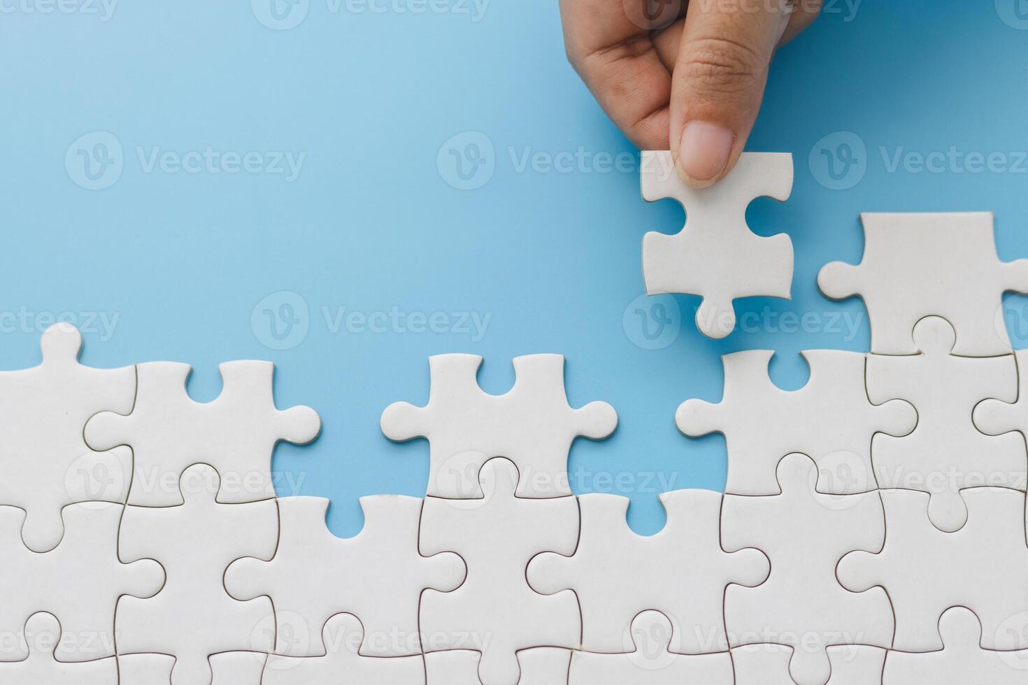 Hand push last piece jigsawto finish success planning concept solve puzzle, logical thinking, Concept of challenge and determination as the person works to complete the puzzle. photo