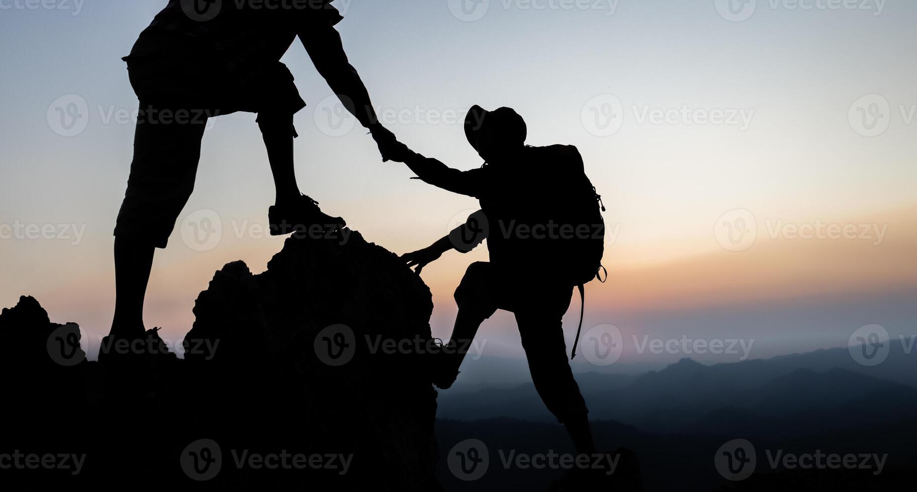 Silhouette of People helping on peak mountain and sunrise background climbing team work success business concept. People on peak mountain climbing helping team work. photo