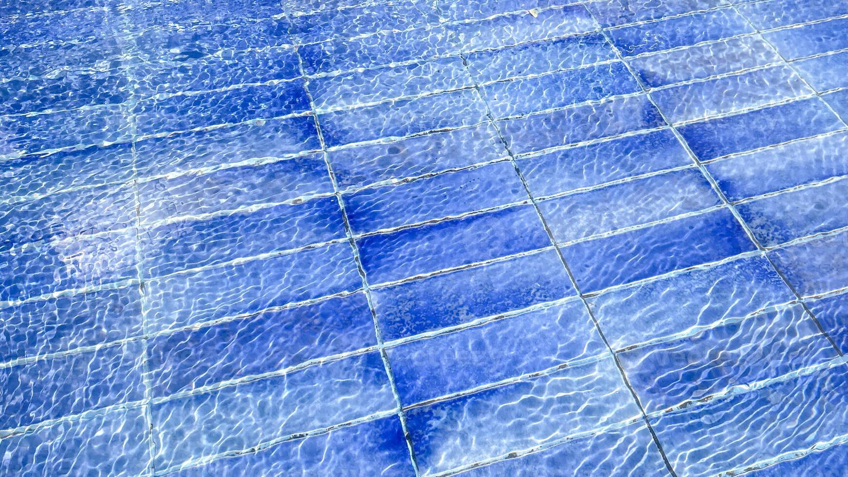 Clear blue water ripples over tiled pool floor, illustrating refreshing summer relaxation and leisure concepts photo