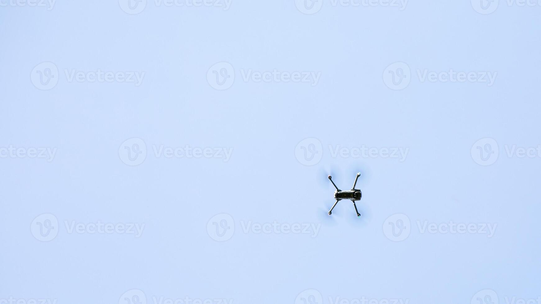A solitary drone flies high against a clear blue sky, symbolizing technology and modern aerial surveillance challenges photo