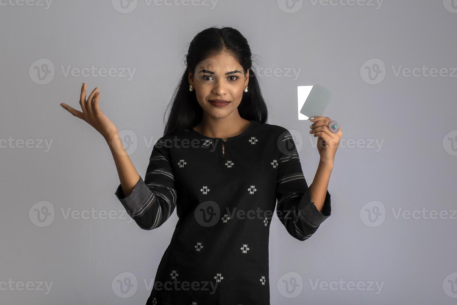 Young smiling beautiful woman or girl presenting credit card in hand showing trust and confidence for making payment. photo