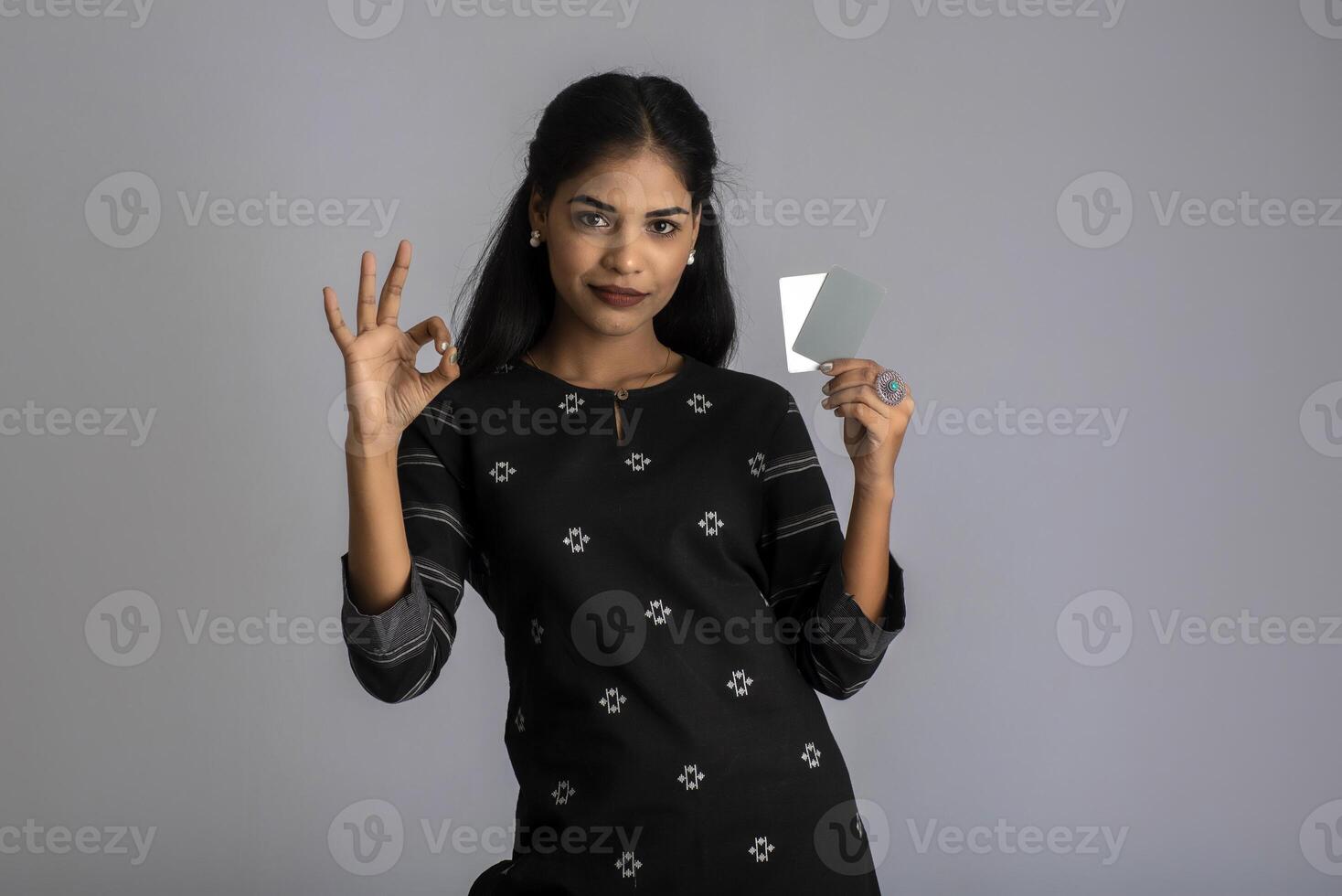 Young smiling beautiful woman or girl presenting credit card in hand showing trust and confidence for making payment. photo