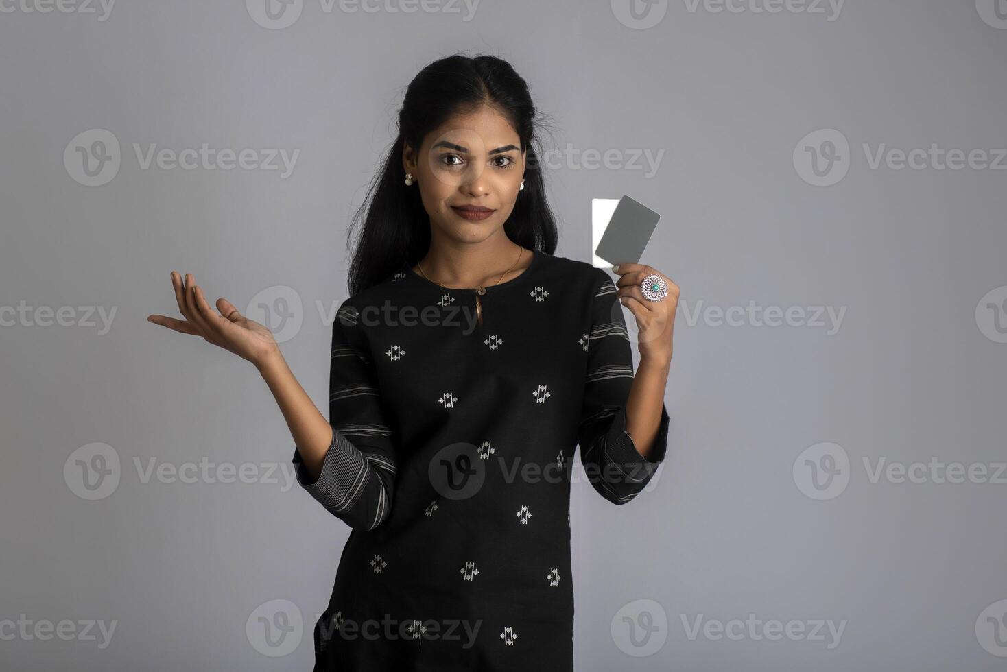 Young smiling beautiful woman or girl presenting credit card in hand showing trust and confidence for making payment. photo