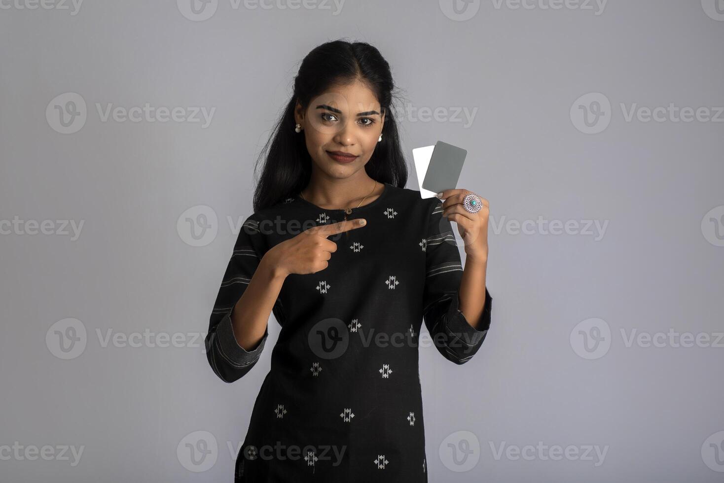 Young smiling beautiful woman or girl presenting credit card in hand showing trust and confidence for making payment. photo