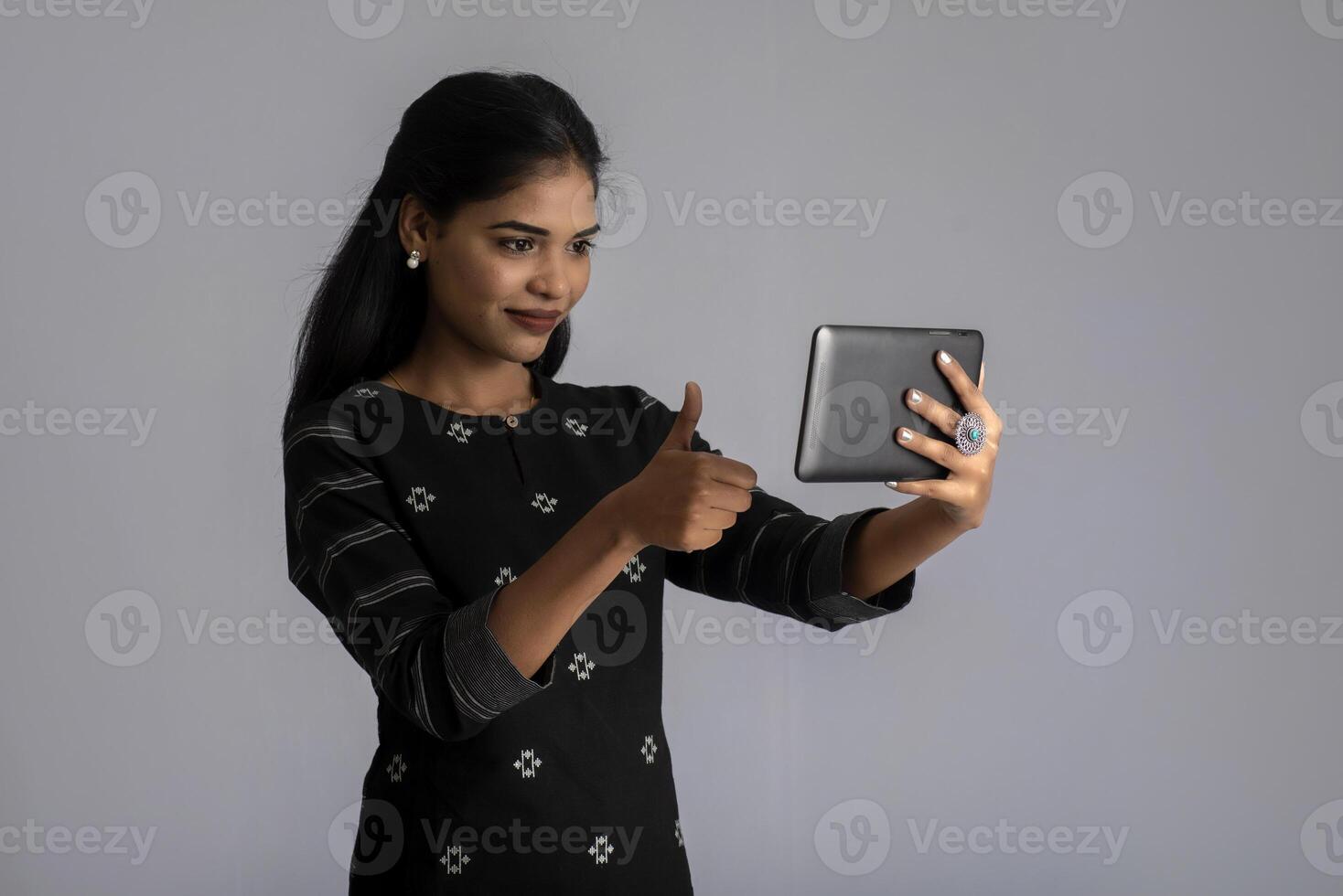 Young Indian girl using a mobile phone or smartphone on gray background photo
