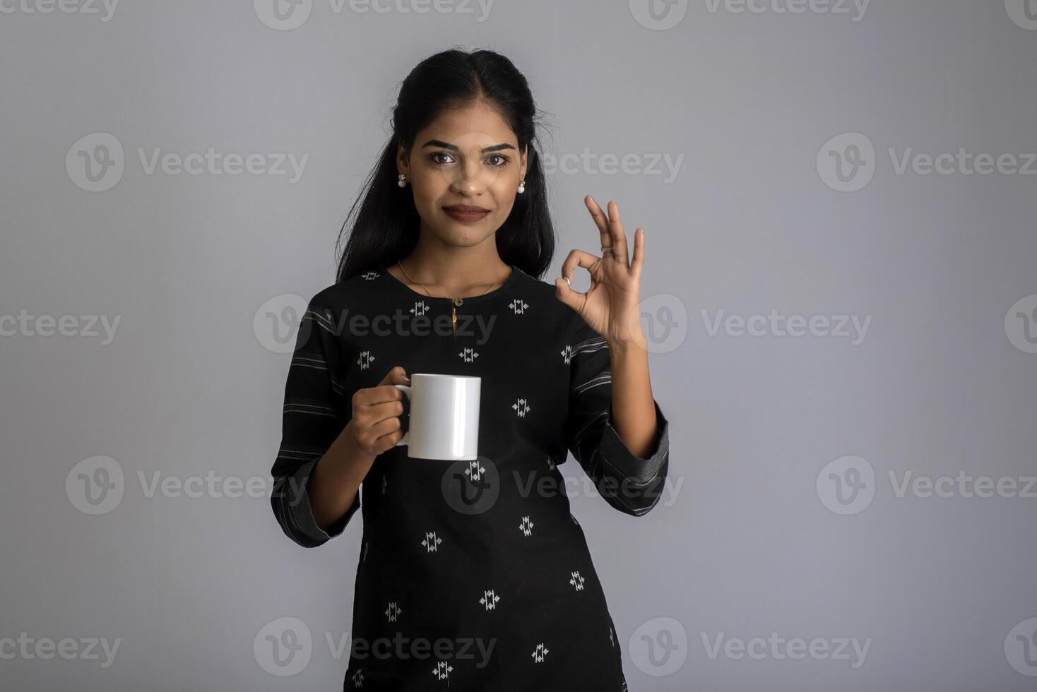 pretty young girl with a cup of tea or coffee posing on grey background photo
