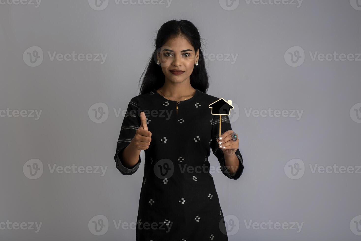A young woman or businesswoman holding a little cutout board in her hands on a gray background. photo