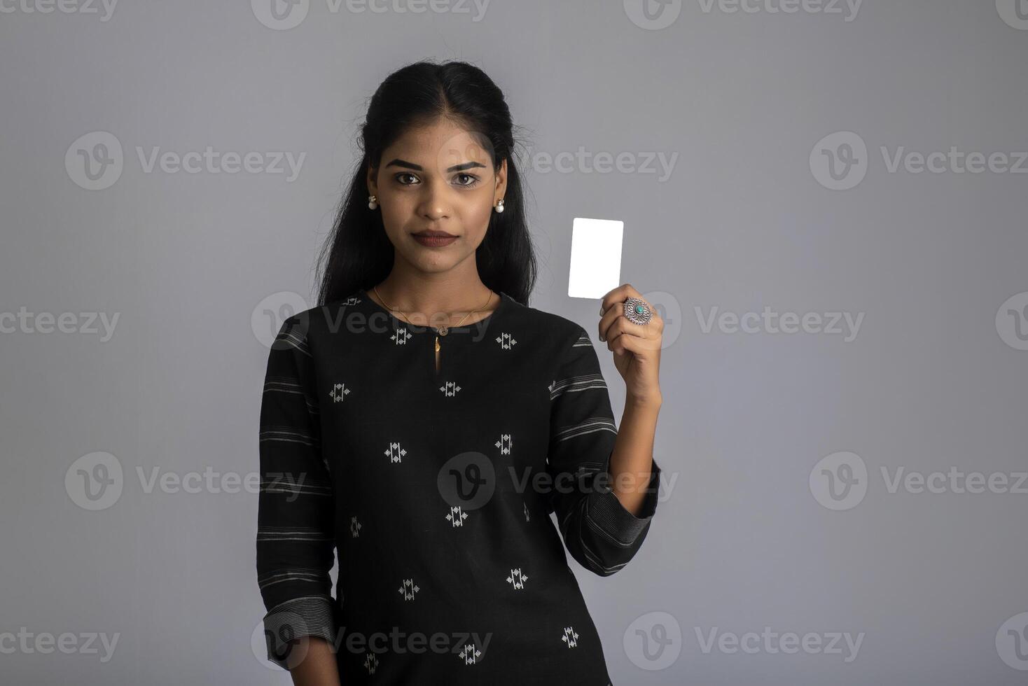 Young smiling beautiful woman or girl presenting credit card in hand showing trust and confidence for making payment. photo