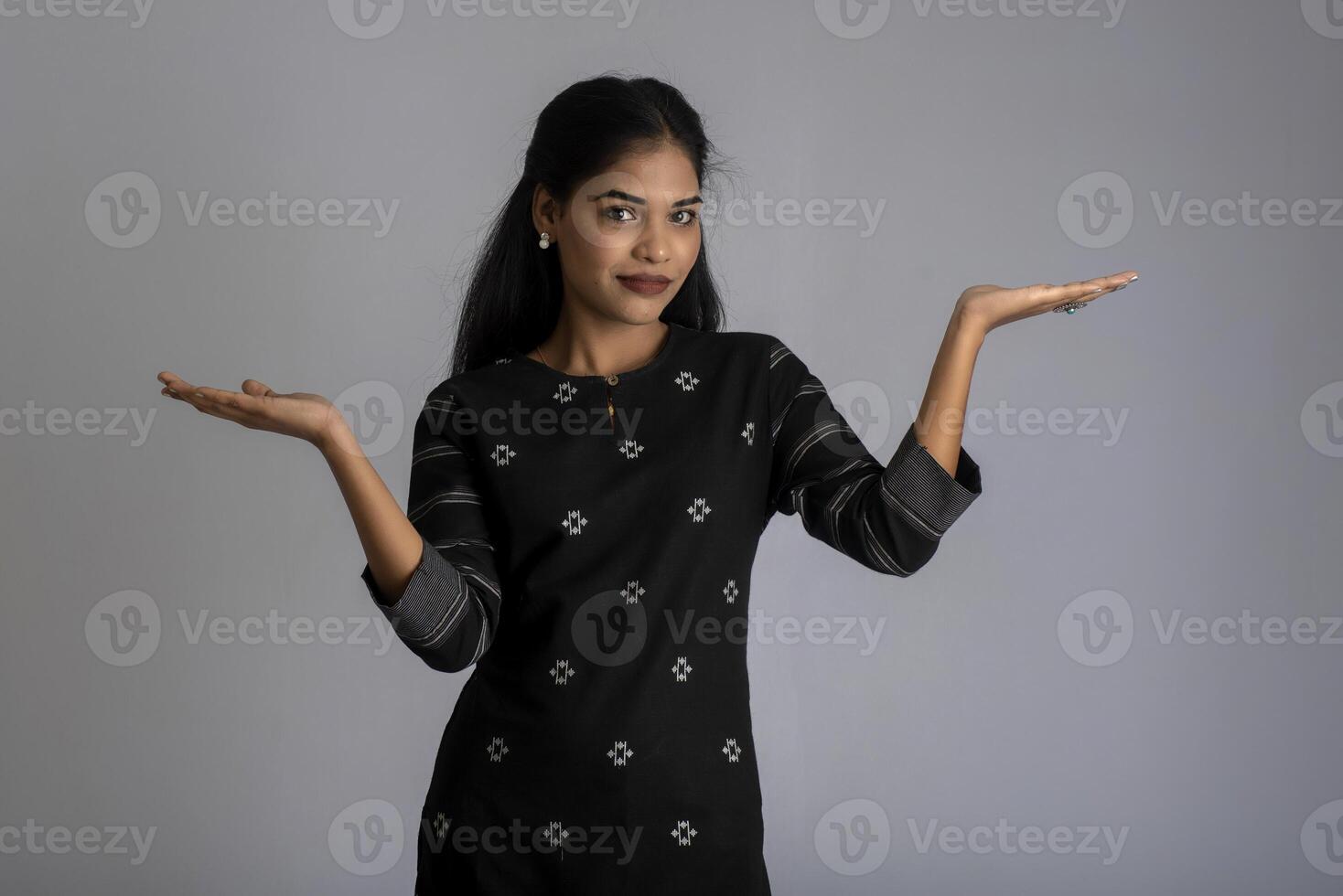 Beautiful girl holding and presenting something in the hand with a happy smiling face. photo