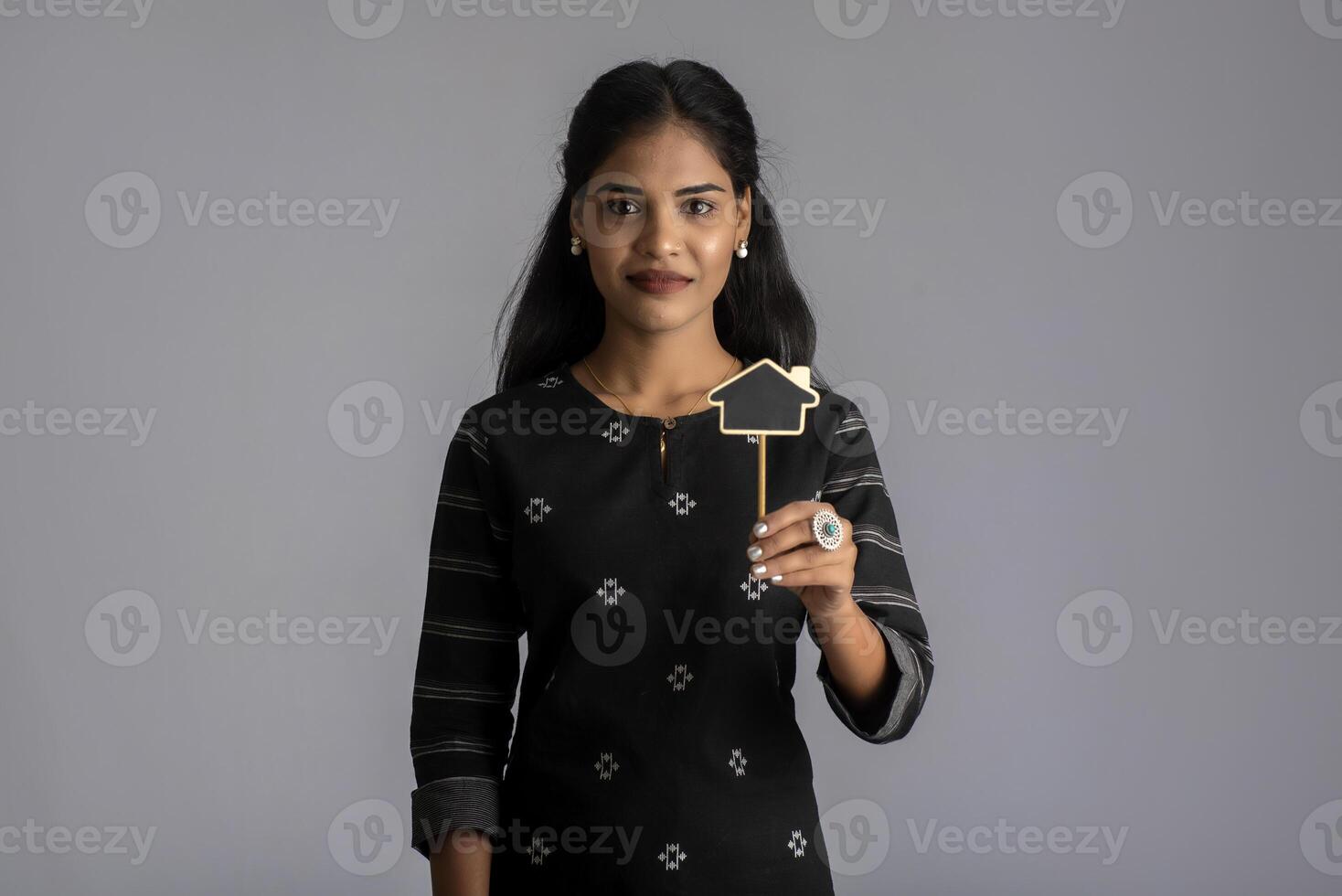 A young woman or businesswoman holding a little cutout board in her hands on a gray background. photo
