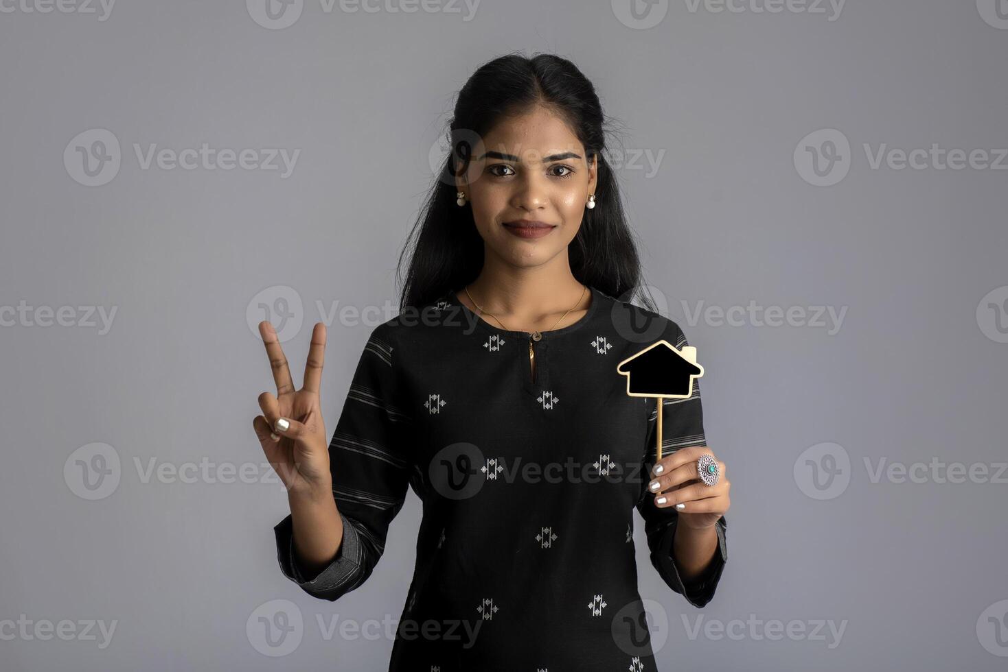 A young woman or businesswoman holding a little cutout board in her hands on a gray background. photo