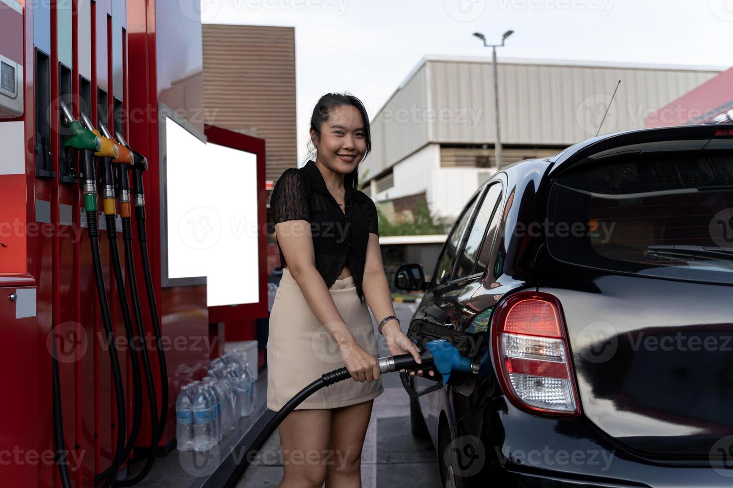 Beautiful woman refueling car. Attractive young woman refueling car at gas station. Female filling diesel at gasoline fuel in car using a fuel nozzle. photo
