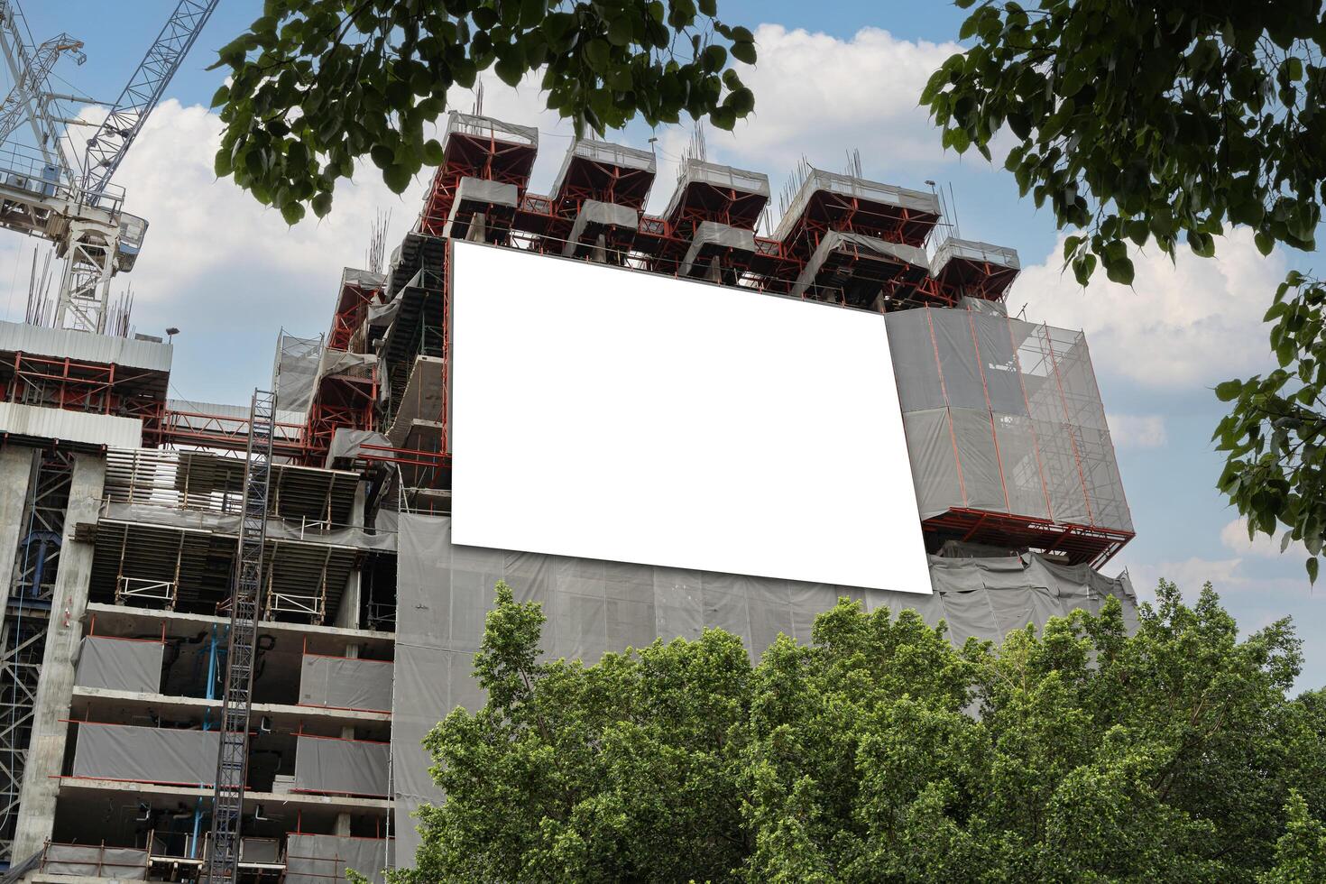 Blank white banner for advertisement hanging on the scaffolding of modern building under construction. White blank information banner mounted on wall. photo