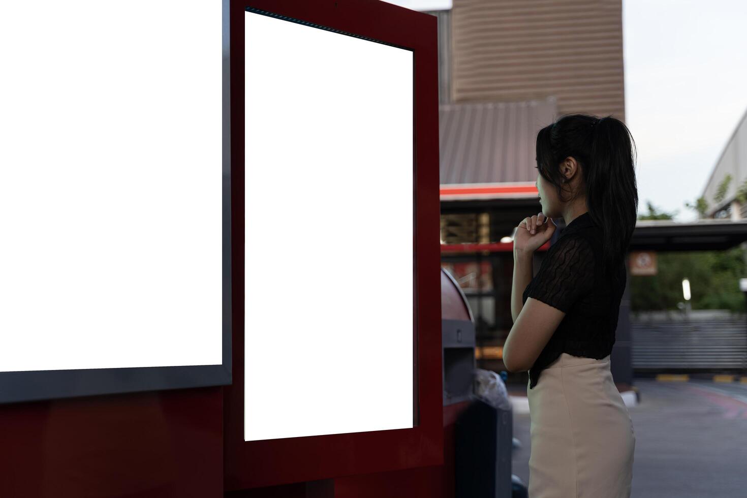 Beautiful woman watching bus movement on electronic bulletin board in unfamiliar city. Young woman traveling using modern digital display with blank space screen. photo
