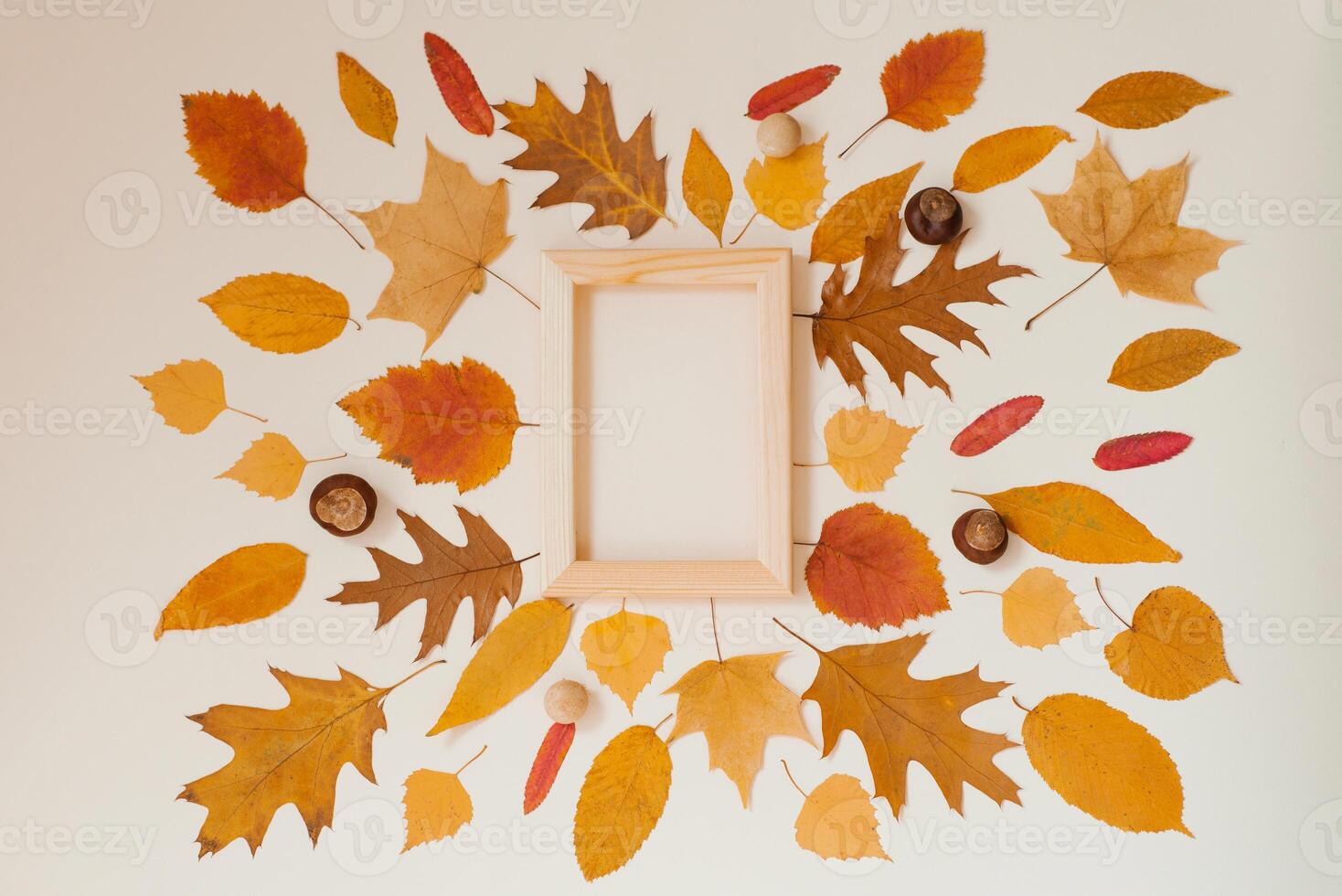 Fallen autumn leaves arranged next to each other around a wooden frame on a beige background. Copy Space photo