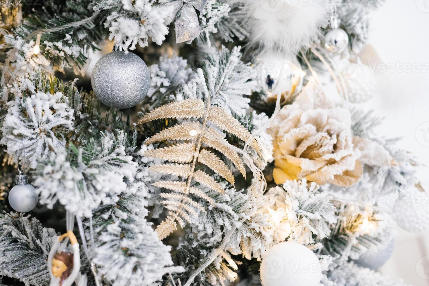 Christmas decorations in the form of a rose, a fern leaf and balls hang on a silver Christmas tree. Christmas background for copy space photo