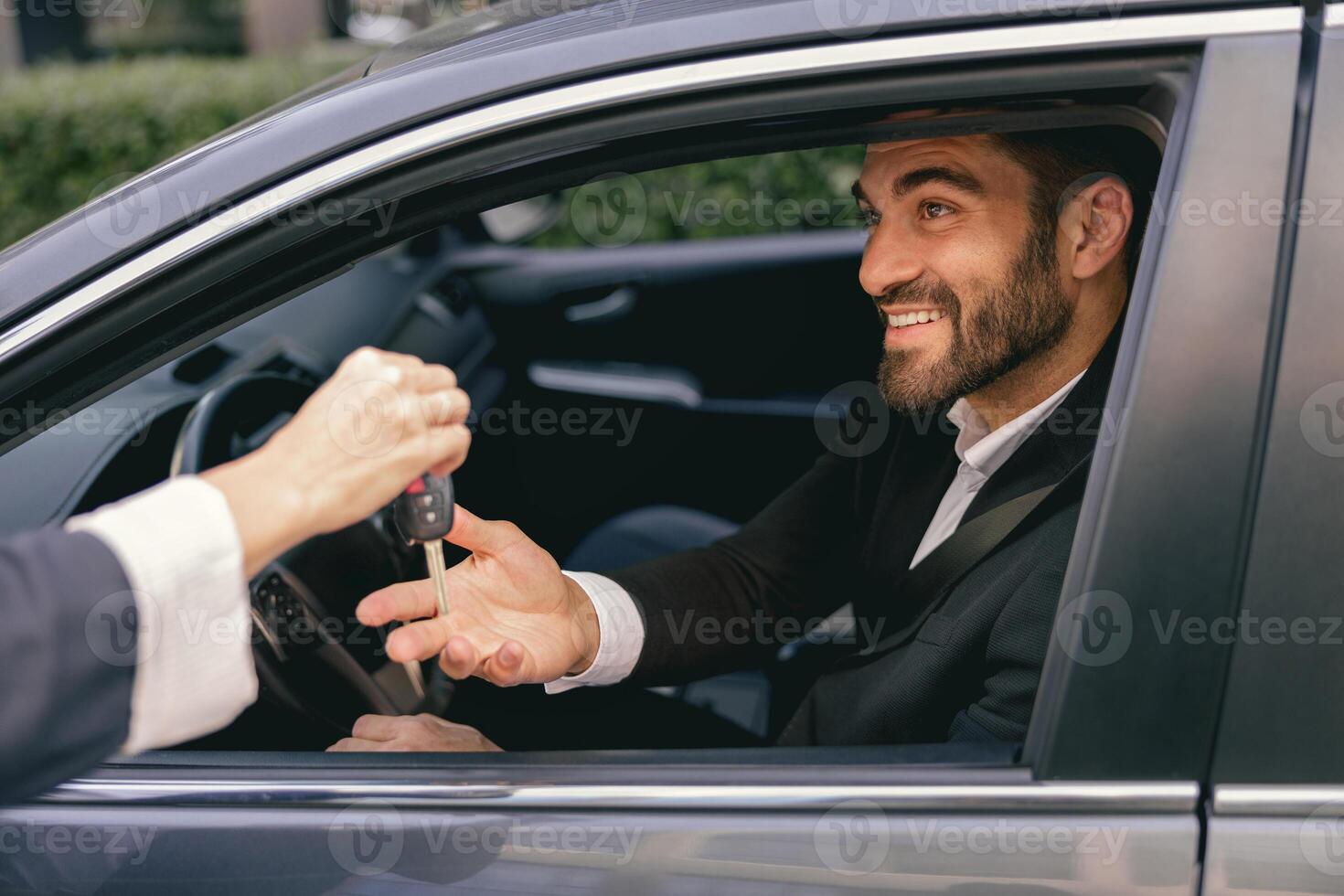 Close up of smiling business man in suit receiving car keys to new vehicle photo