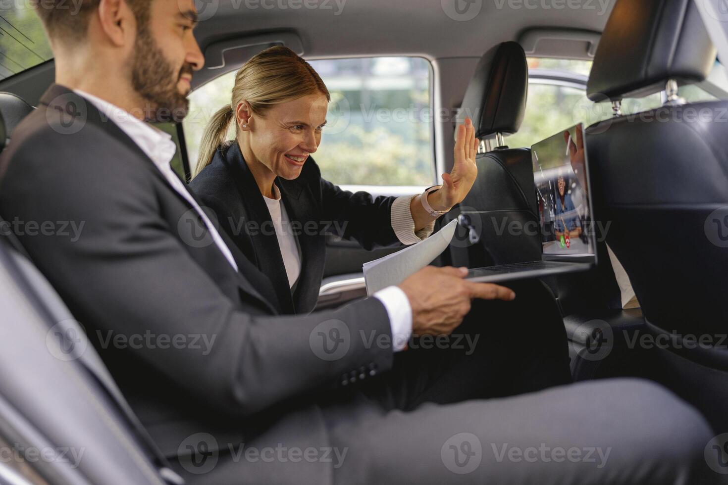 Cheerful business people have online meeting using laptop while sitting in car back seats photo