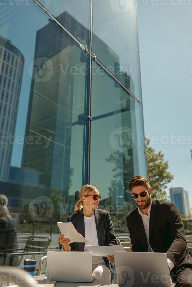 Business colleagues working with documents sitting outside of office on cafe terrace photo