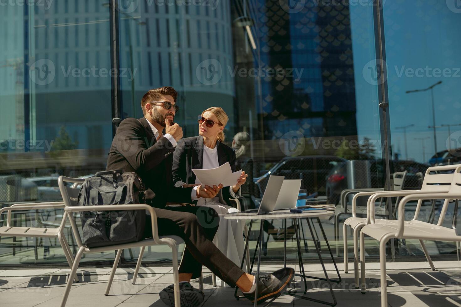 Two business partners working with documents sitting outside of office on cafe terrace photo