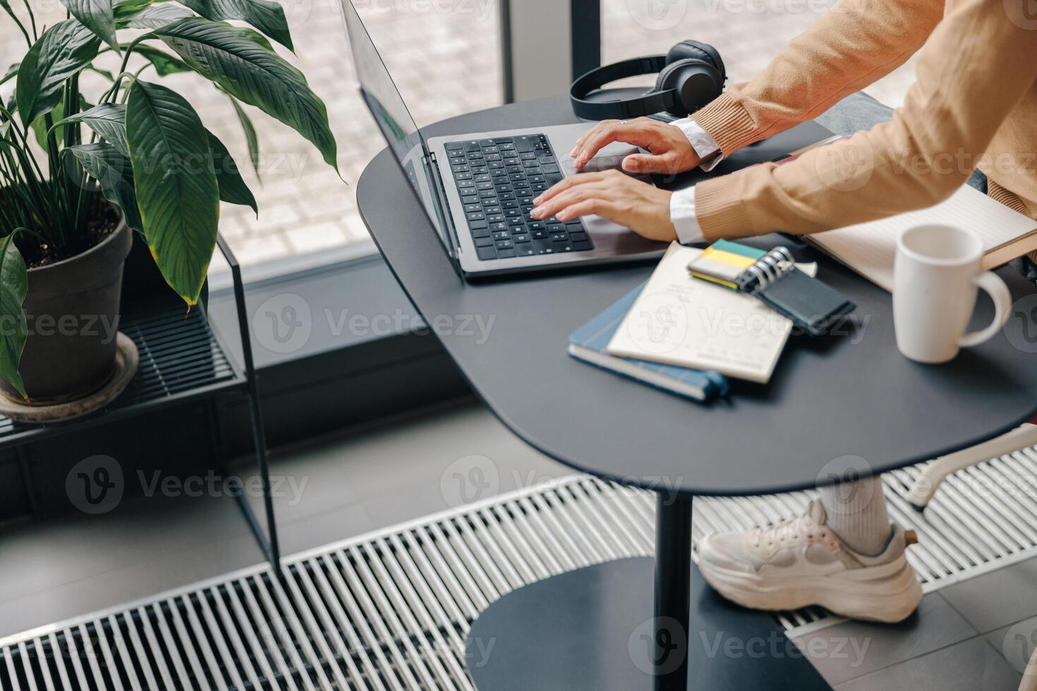 Close up of female freelancer working on laptop sitting in coworking near window photo