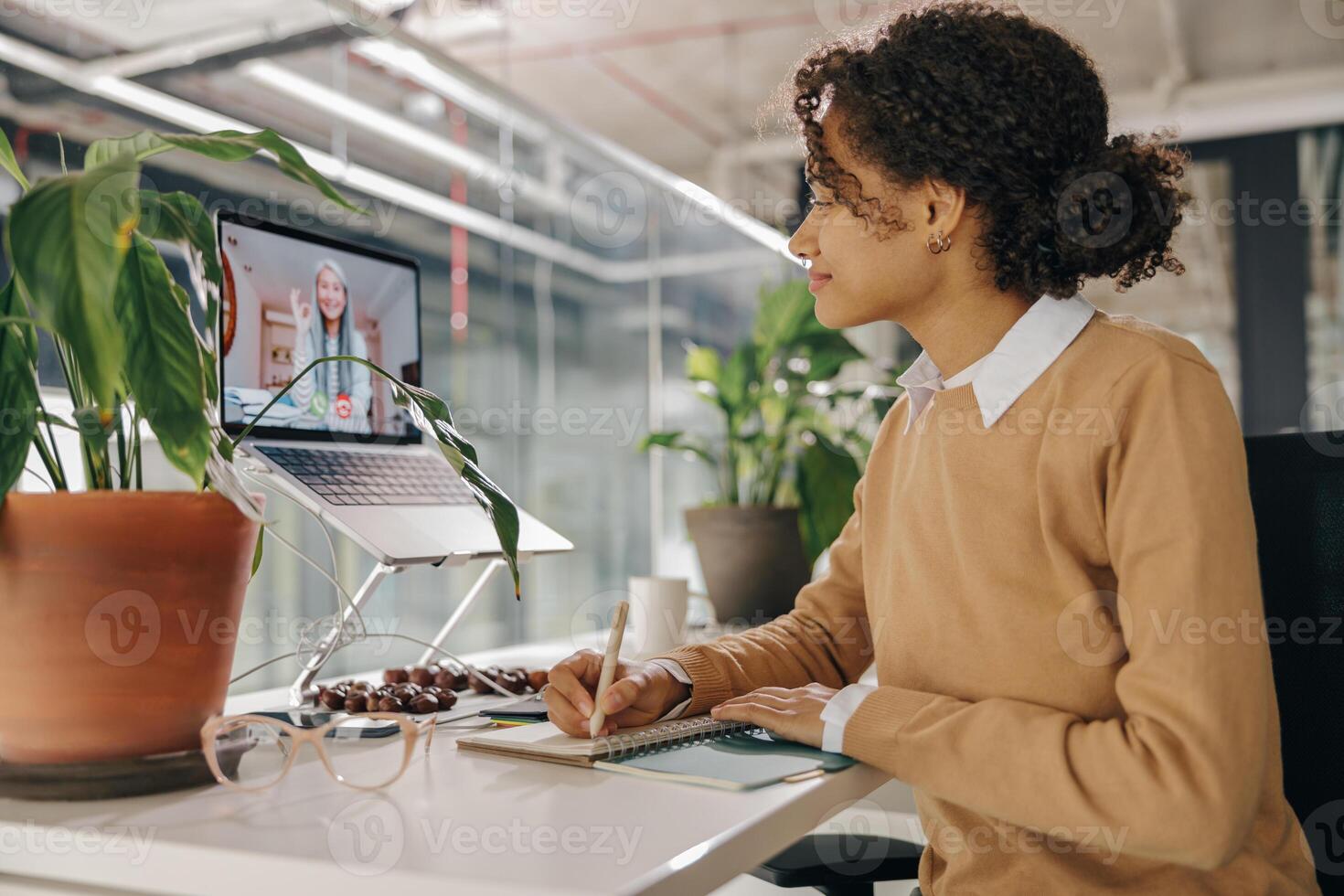 Female freelancer have conference with client and making notes sitting in cozy coworking photo