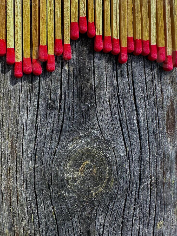 A closeup of matches scattered on a rustic wooden surface, showcasing the rich texture and warm colors. Perfect for themes of safety and simplicity. photo