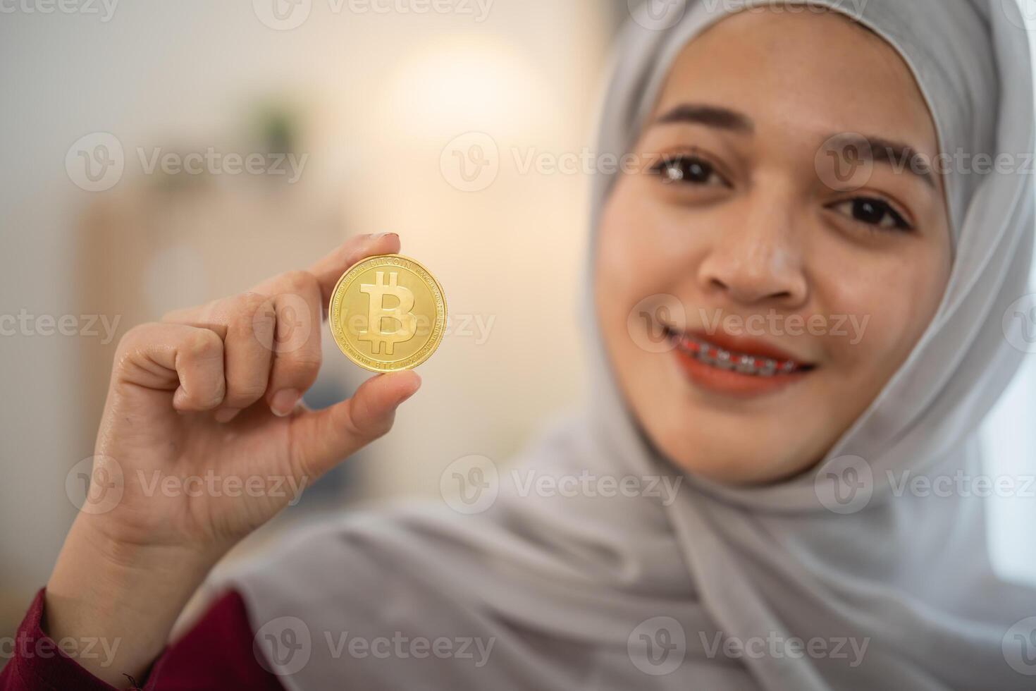 Muslim islam woman with hijab is holding a gold coin with the letter B on it. She is smiling and she is happy photo