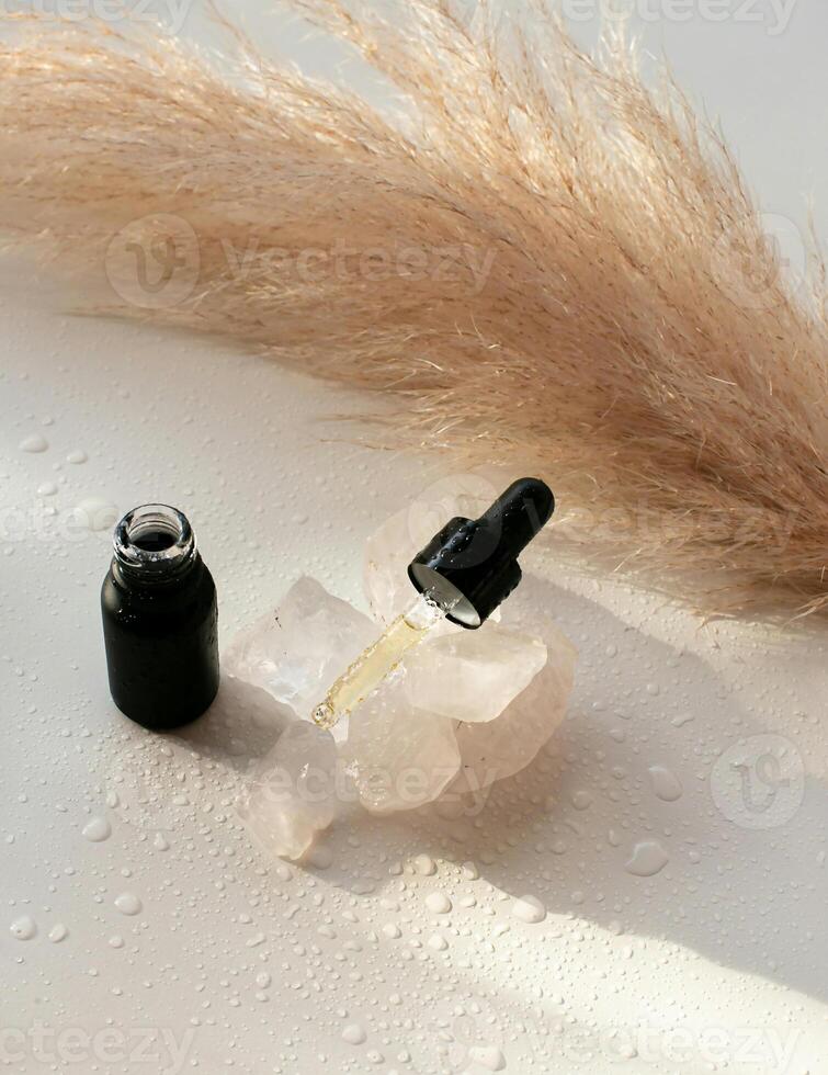 a bottle of oil and a rock sitting on a white surface photo