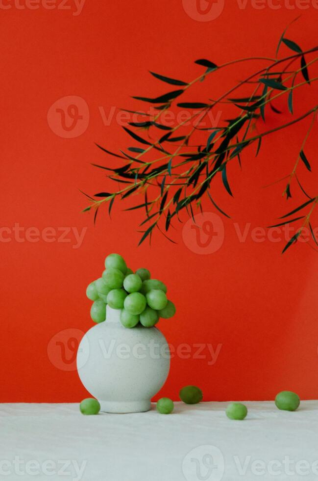 a white vase with green grapes in it photo