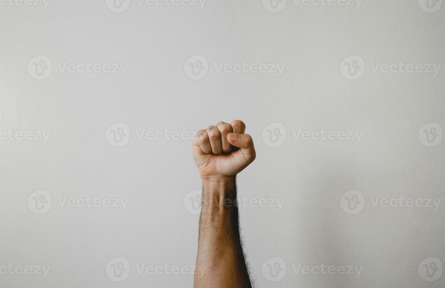 a person holding up their fist in front of a white wall photo