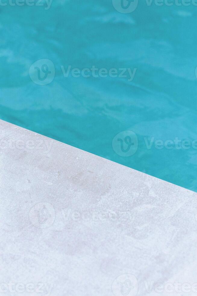 a dog is sitting on a ledge near a pool photo