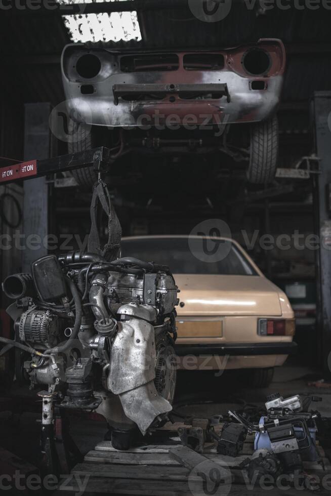 Engine on the crane and classic cars on a ramp in a background in the garage. photo