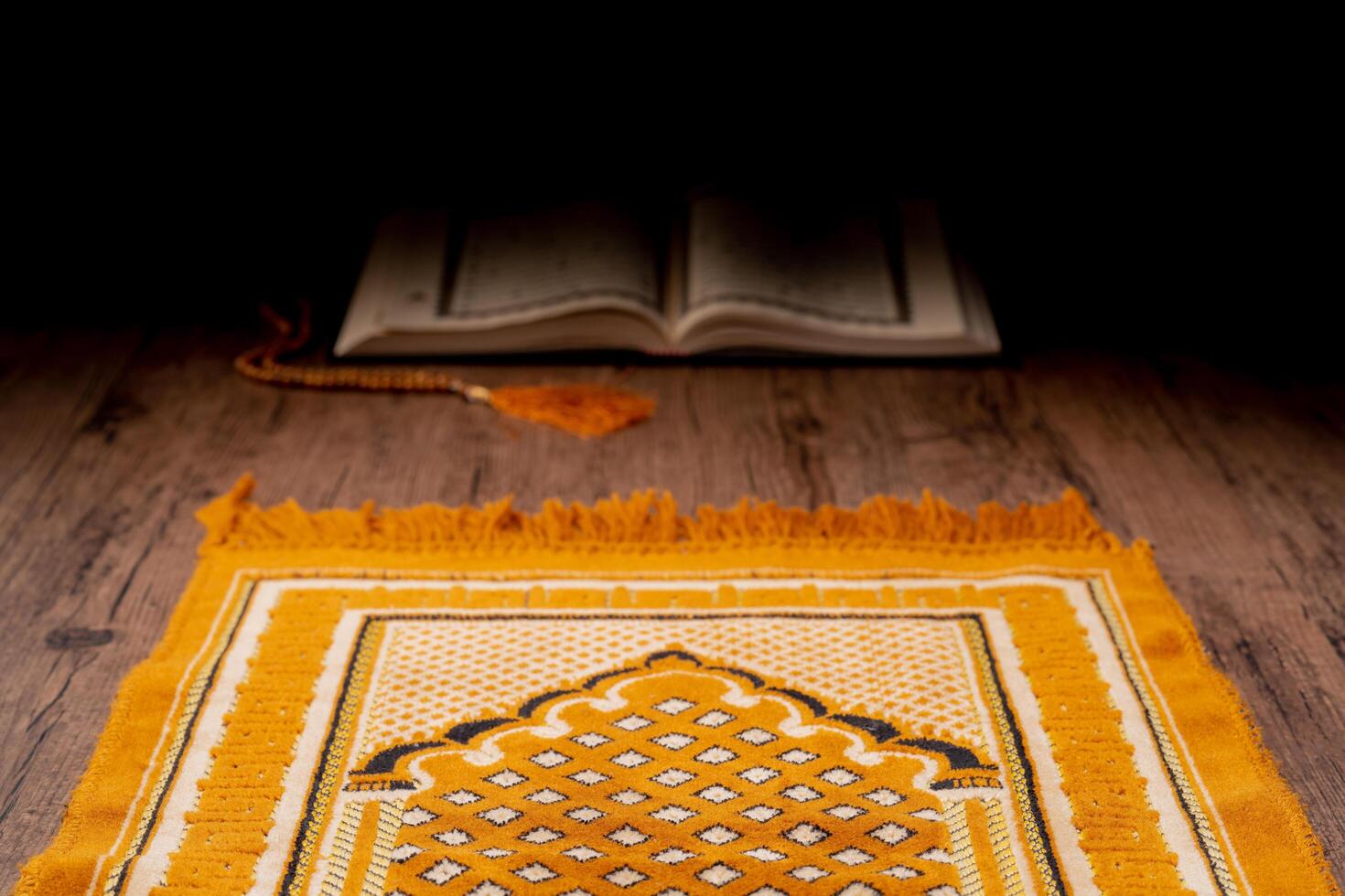 A Asian Muslim woman is sitting and reading the Quran at the wooden table at his house during the night during the month of ramadan, Arabic calligraphy meaning of Al Quran. photo