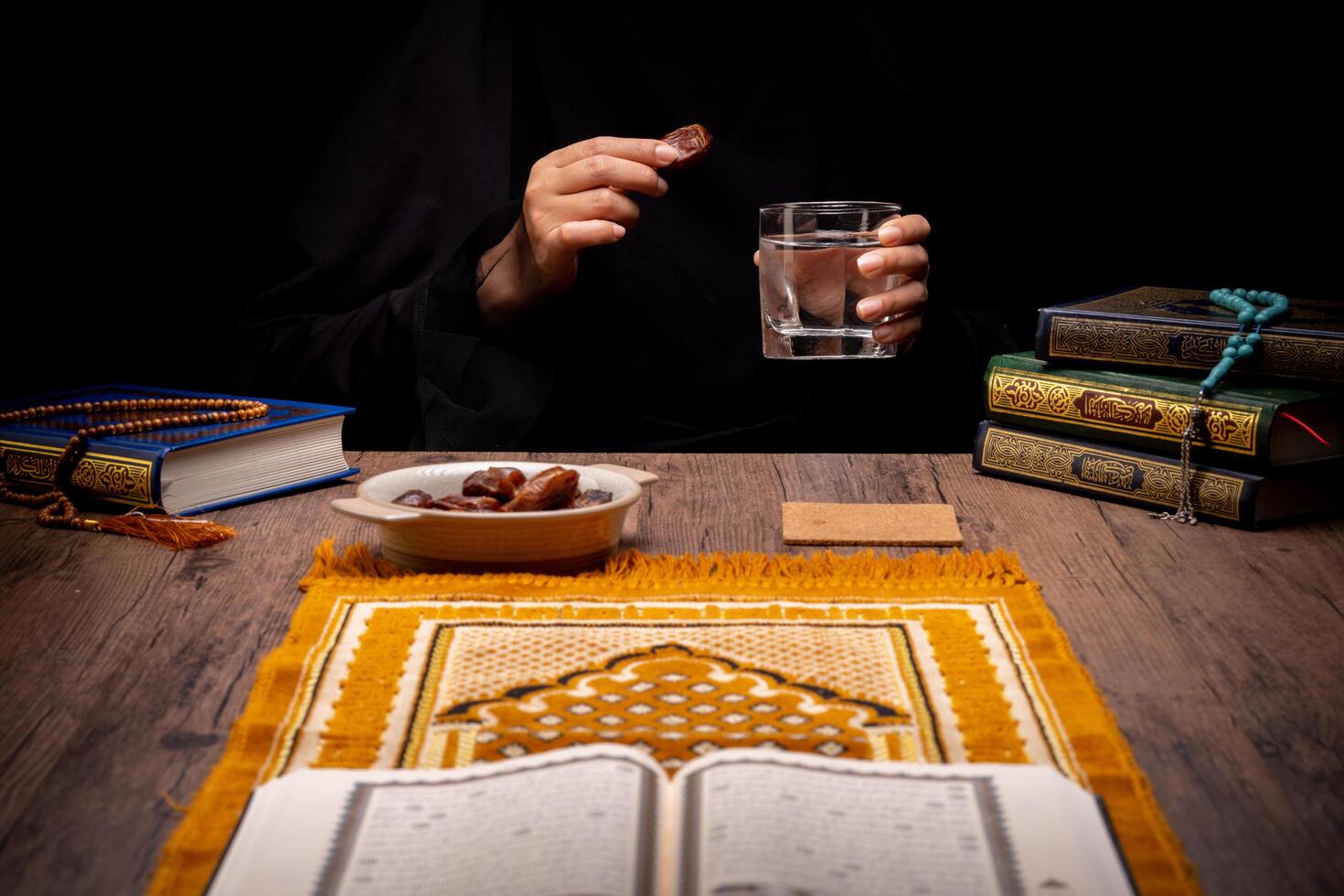 Many Date Palms are on bowls, plates, and cups of water, and the Quran is on wooden tables, to wait for the time of Iftar, with the concept of ramadan Muslims, Arabic calligraphy meaning of Al Quran photo