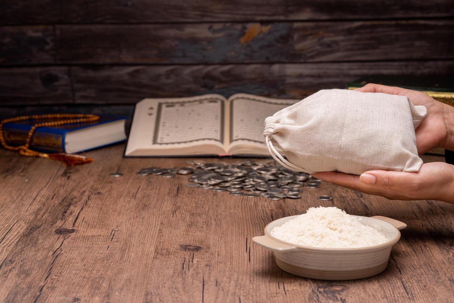 Hands holding a wooden bowl of rice grains and money bag for zakat, Islamic zakat concept. Muslims help the poor and needy. Conceptual shoot for property, income, and fitrah zakat. photo
