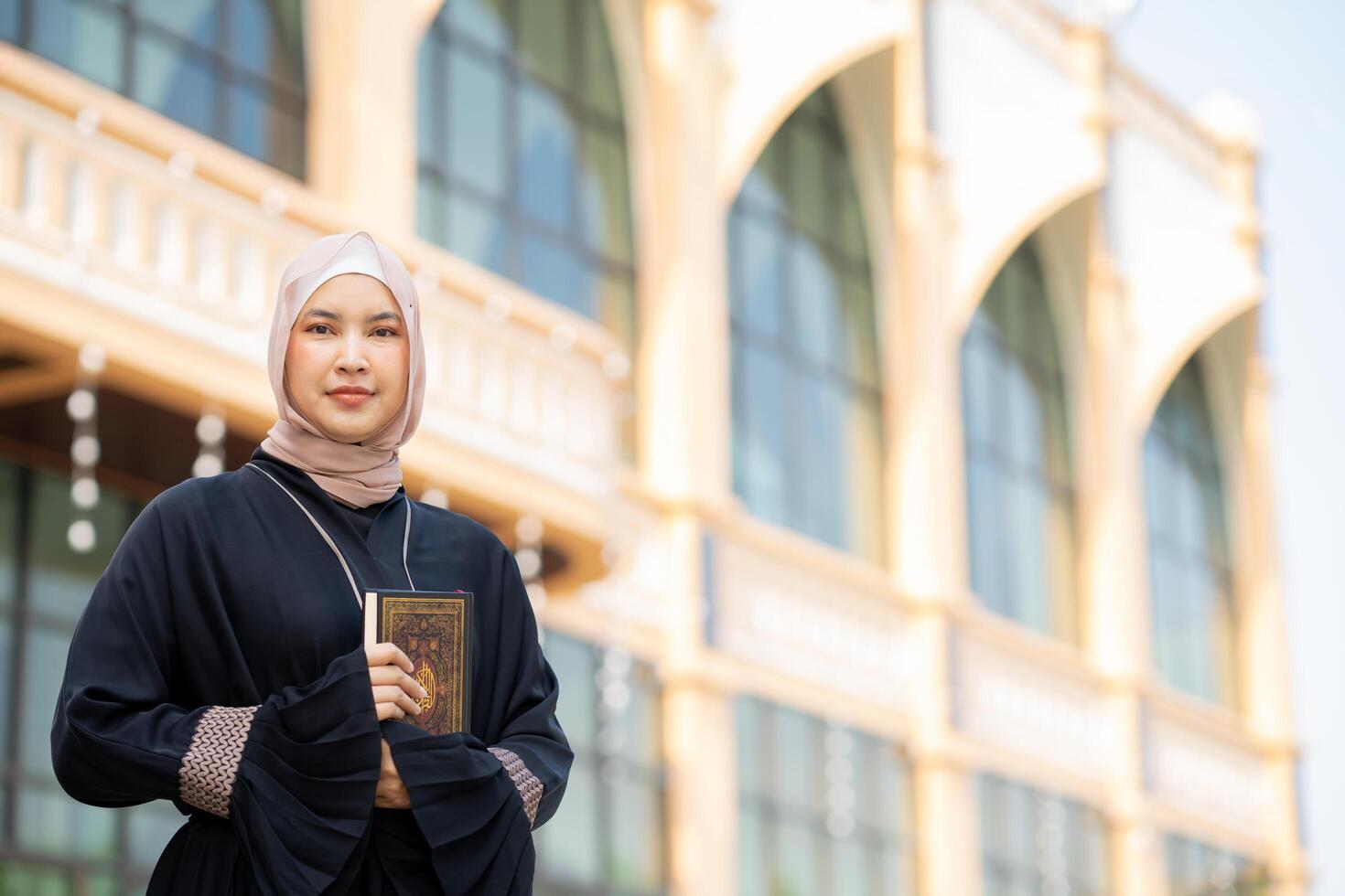 The image of an Asian Muslim woman in the Islamic religion in hijab in cream color. reading the Quran and having a happy smiling face Staying in a beautiful mosque out of respect for God. photo